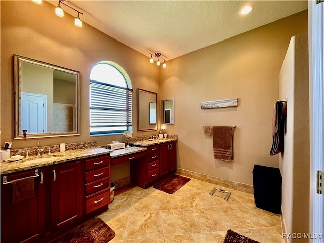 bathroom featuring rail lighting, vanity, a textured ceiling, and tile patterned floors