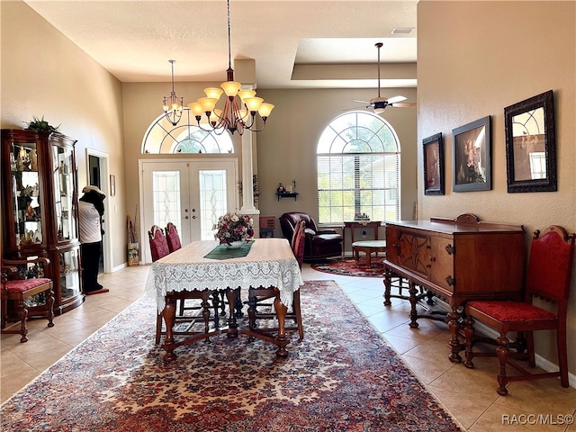 tiled dining area featuring a textured ceiling, french doors, and ceiling fan with notable chandelier