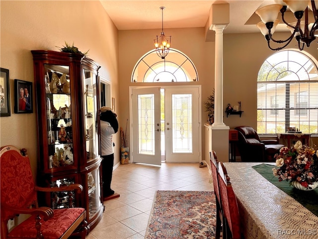 entrance foyer with a chandelier, french doors, ornate columns, and light tile patterned flooring