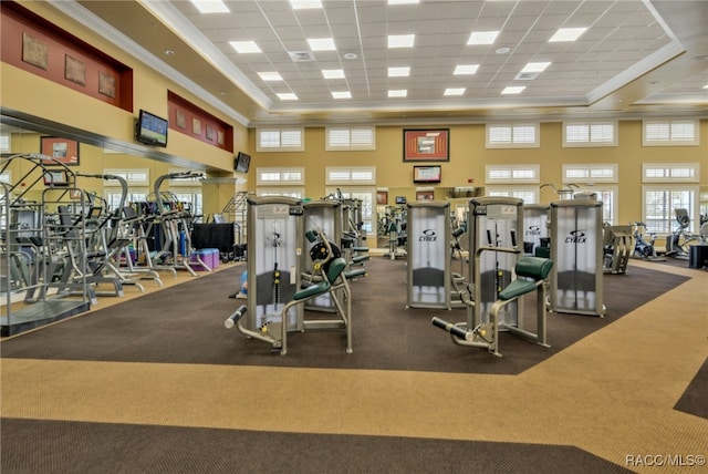 gym with a high ceiling, a paneled ceiling, a tray ceiling, and crown molding