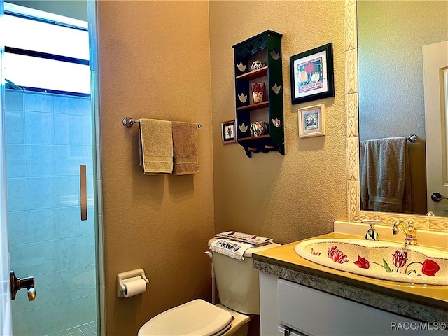 bathroom featuring vanity, toilet, and tiled shower