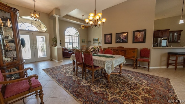 tiled dining area featuring french doors, decorative columns, a wealth of natural light, and a high ceiling