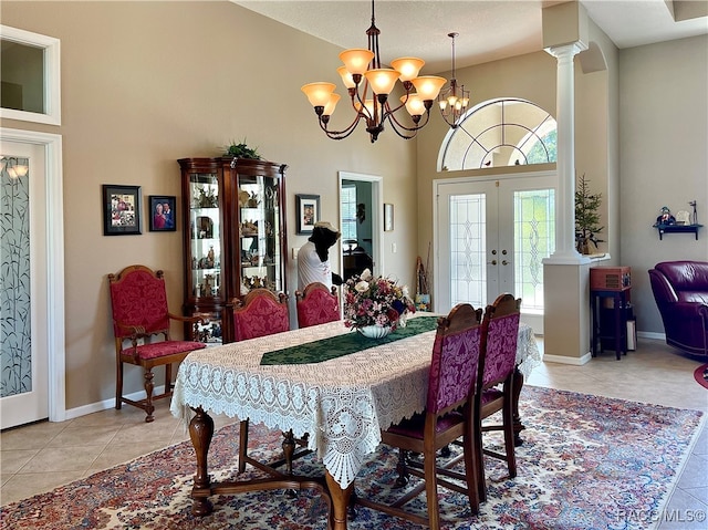 dining area featuring french doors, a towering ceiling, decorative columns, light tile patterned floors, and a notable chandelier