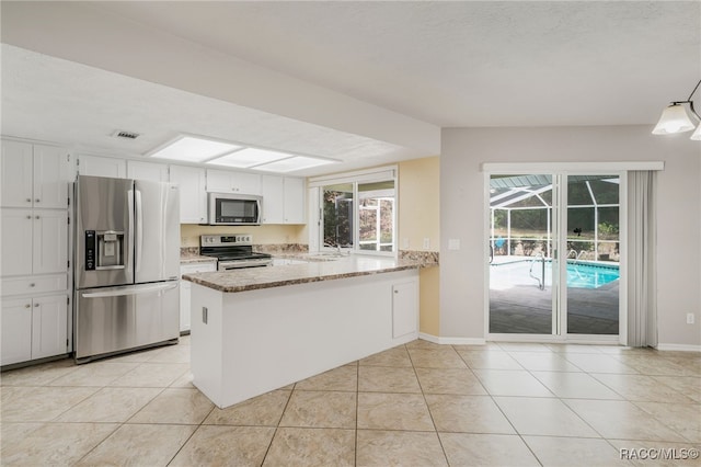 kitchen featuring light stone countertops, appliances with stainless steel finishes, a peninsula, white cabinetry, and light tile patterned floors
