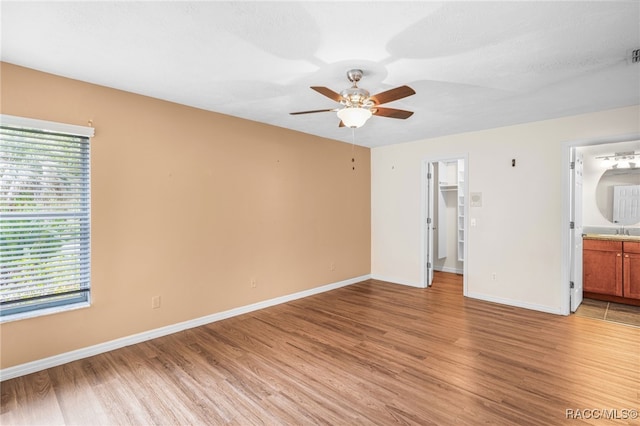 unfurnished bedroom with a sink, baseboards, and light wood-type flooring