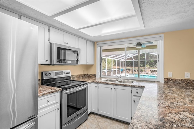 kitchen featuring a sink, a ceiling fan, white cabinets, and stainless steel appliances