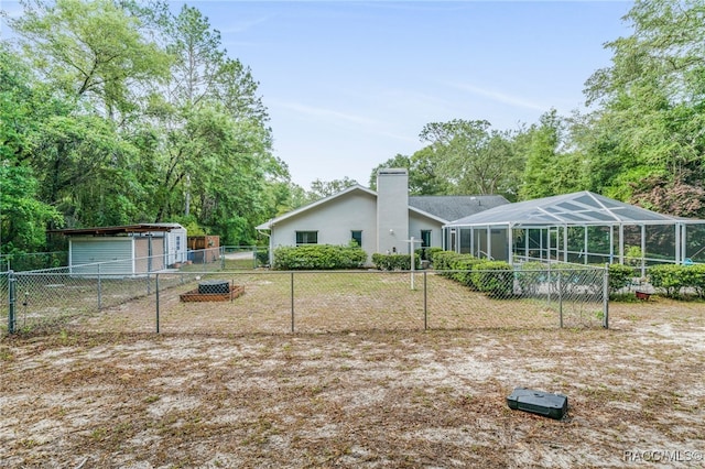 rear view of property featuring a fenced backyard, a lanai, a chimney, and an outdoor structure