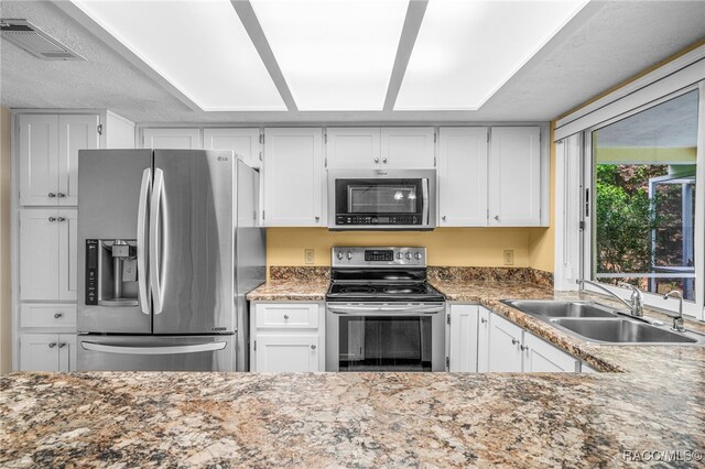 kitchen with white cabinets, stainless steel appliances, visible vents, and a sink
