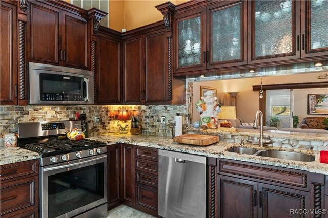 kitchen featuring tasteful backsplash, light stone counters, sink, and appliances with stainless steel finishes