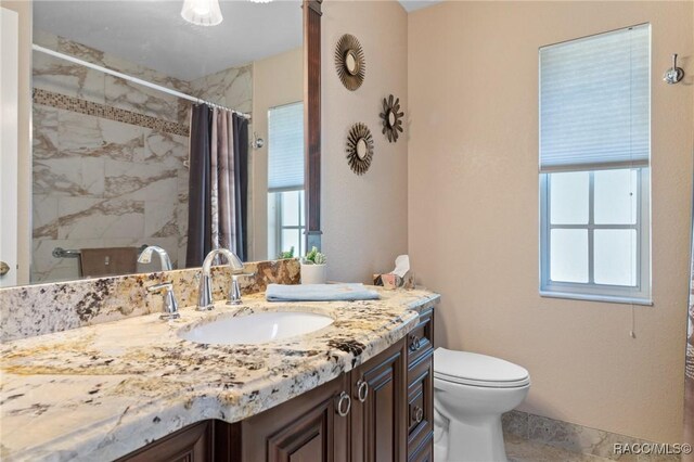 bathroom with plenty of natural light, curtained shower, toilet, and vanity