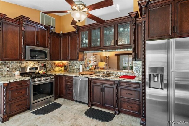 kitchen with stainless steel appliances, light stone counters, tasteful backsplash, and sink