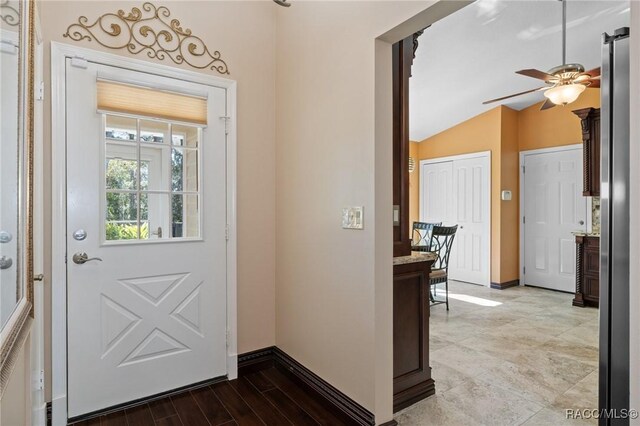 doorway featuring light hardwood / wood-style flooring, vaulted ceiling, and ceiling fan