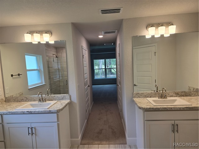 bathroom featuring vanity, a healthy amount of sunlight, a textured ceiling, and tiled shower