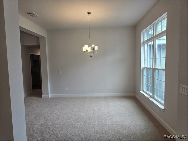 carpeted empty room with an inviting chandelier