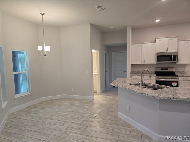 kitchen with light stone countertops, sink, stainless steel appliances, pendant lighting, and white cabinets