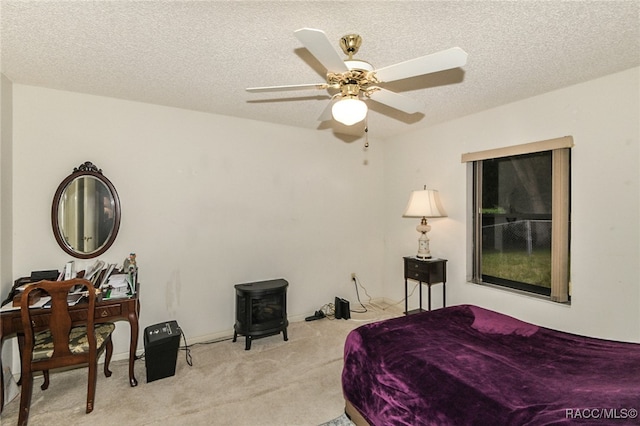 carpeted bedroom featuring a textured ceiling, a wood stove, and ceiling fan