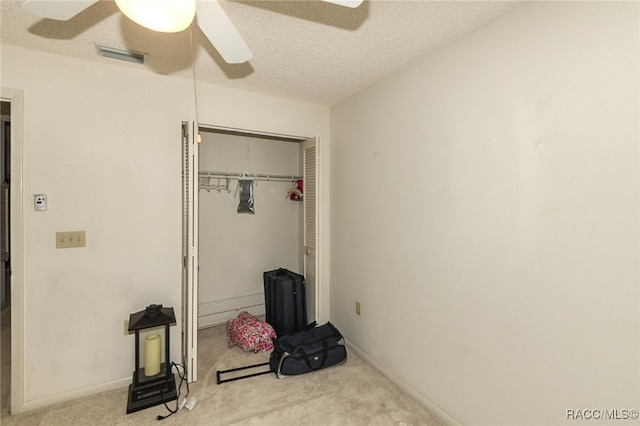 carpeted bedroom featuring ceiling fan, a closet, and a textured ceiling