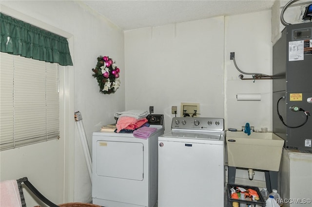 laundry area with a textured ceiling, independent washer and dryer, and sink