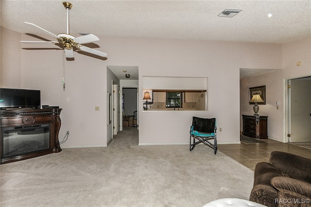 carpeted living room with ceiling fan and a textured ceiling