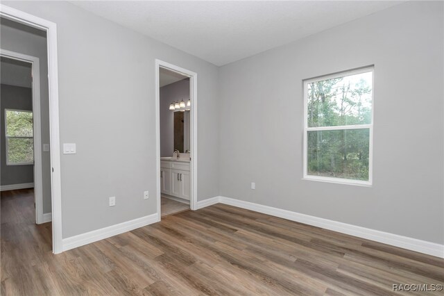 7024 N Fountainhead Dr, Citrus Springs, FL 34433 - unfurnished bedroom with multiple windows, wood finished floors, and connected bathroom