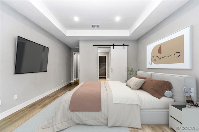 7024 N Fountainhead Dr, Citrus Springs, FL 34433 - bedroom featuring a barn door, a raised ceiling, wood finished floors, a walk in closet, and recessed lighting