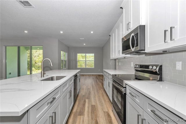 7024 N Fountainhead Dr, Citrus Springs, FL 34433 - kitchen with appliances with stainless steel finishes, light wood-style flooring, recessed lighting, tasteful backsplash, and light stone countertops