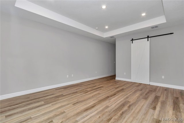 7024 N Fountainhead Dr, Citrus Springs, FL 34433 - unfurnished bedroom with a raised ceiling, a barn door, recessed lighting, and light wood finished floors