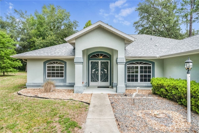 2617 E Newhaven St, Inverness, FL 34453 - view of exterior entry with roof with shingles, stucco siding, and a lawn