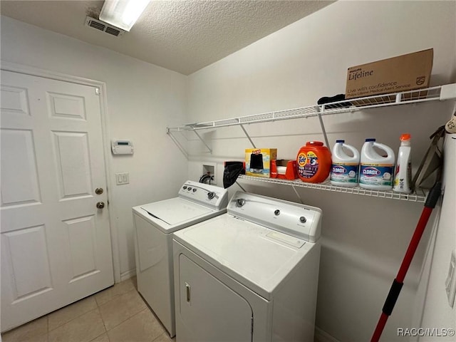 laundry room with separate washer and dryer, light tile patterned floors, a textured ceiling, visible vents, and laundry area