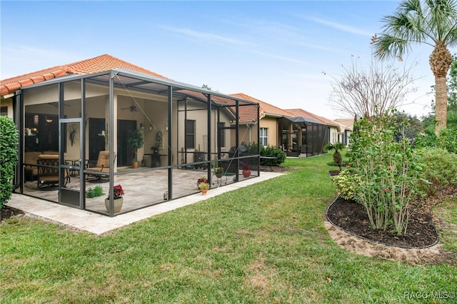 rear view of property with a lanai, a patio area, and a lawn