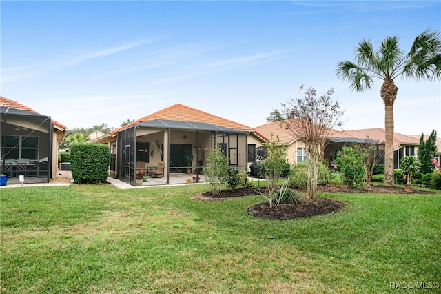 rear view of house featuring a lawn and glass enclosure