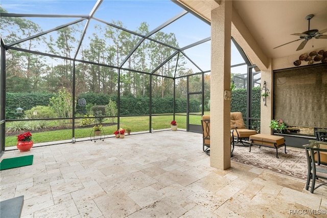 view of patio with ceiling fan and glass enclosure