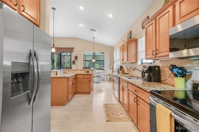 kitchen with lofted ceiling, sink, light stone countertops, decorative light fixtures, and stainless steel appliances