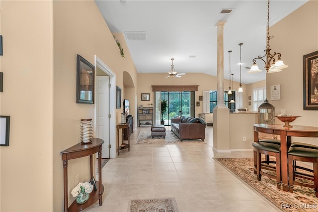 tiled entryway with decorative columns, lofted ceiling, and ceiling fan with notable chandelier