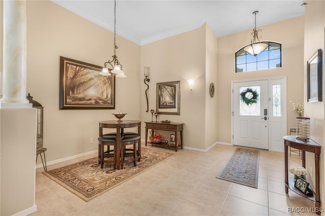 foyer with light tile patterned floors, a towering ceiling, decorative columns, and crown molding