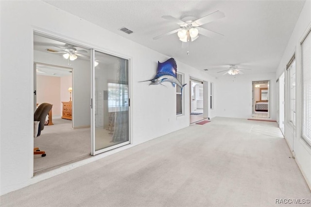 carpeted empty room with visible vents and a ceiling fan