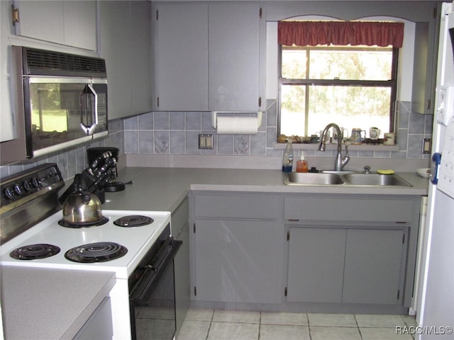 kitchen with sink, backsplash, light tile patterned floors, and white range with electric cooktop