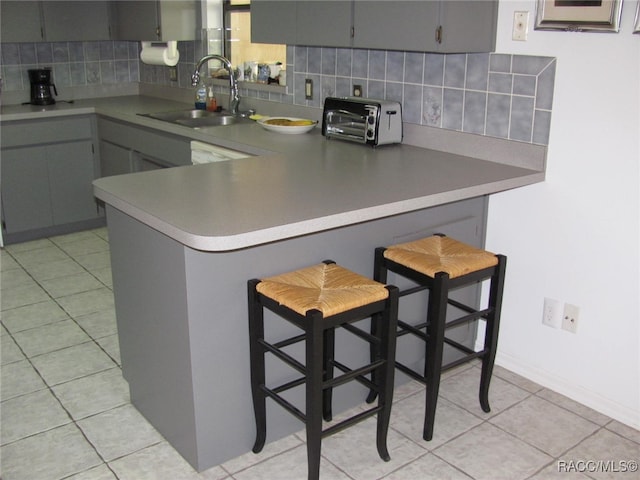 kitchen with sink, backsplash, kitchen peninsula, and a breakfast bar