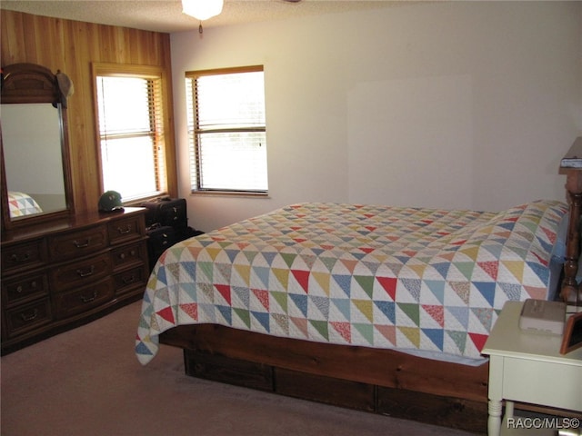 carpeted bedroom featuring wooden walls