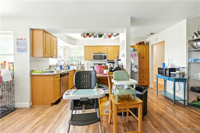kitchen featuring appliances with stainless steel finishes, light wood-style floors, light countertops, and baseboards