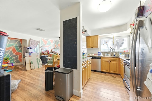 kitchen featuring stainless steel appliances, light wood-style floors, a sink, and light brown cabinets