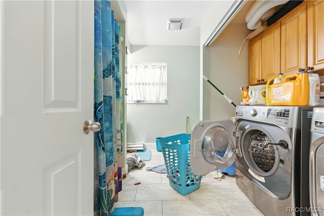 laundry area with washing machine and clothes dryer, cabinet space, and tile patterned flooring