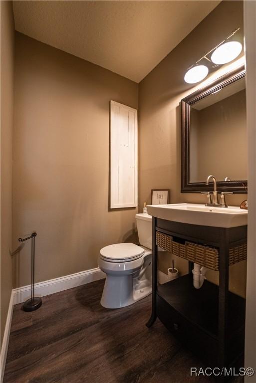 bathroom with hardwood / wood-style floors, vanity, lofted ceiling, and toilet