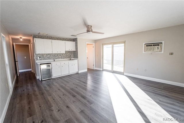 kitchen with backsplash, beverage cooler, dark wood-type flooring, an AC wall unit, and white cabinets