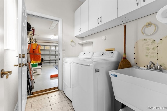 laundry area with cabinets, light tile patterned flooring, washer and clothes dryer, and sink