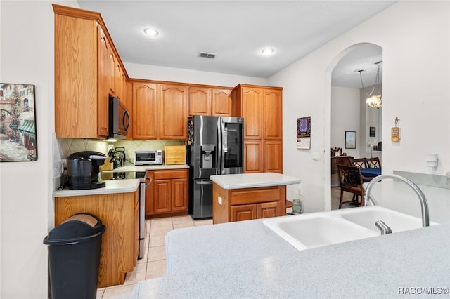 kitchen with stainless steel appliances, sink, light tile patterned floors, a notable chandelier, and a kitchen island