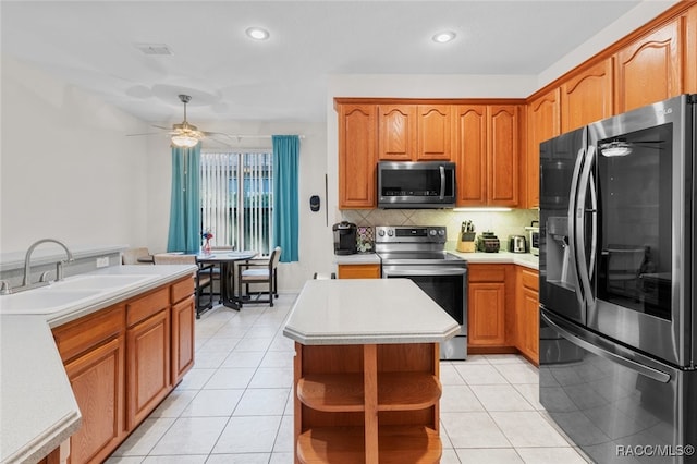 kitchen featuring a center island, sink, ceiling fan, light tile patterned floors, and stainless steel appliances