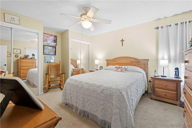 bedroom with ceiling fan, light carpet, and a textured ceiling