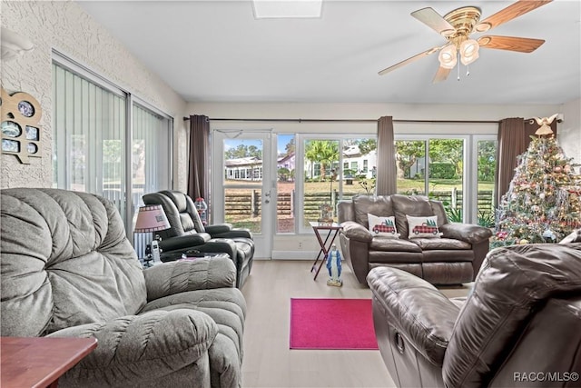 living room with ceiling fan, plenty of natural light, and light wood-type flooring