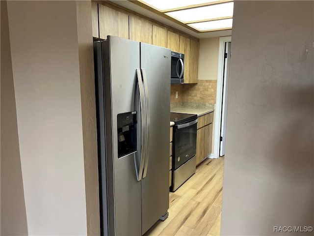 kitchen featuring decorative backsplash, appliances with stainless steel finishes, and light hardwood / wood-style floors